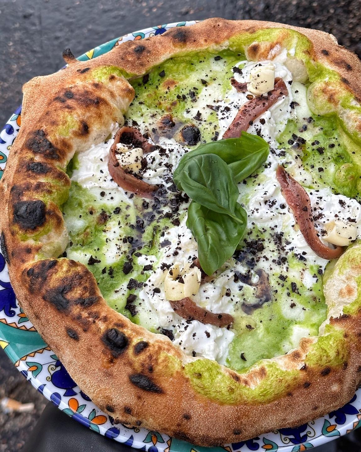 Pizza gourmet con crema verde e ingredienti selezionati